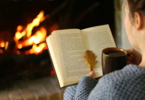 Femme lisant devant un feu de cheminée